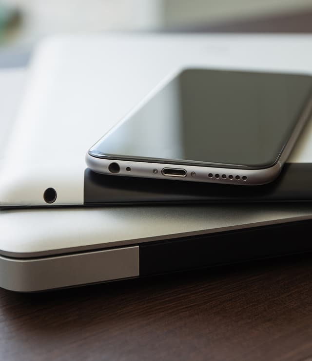 테이블 위에 포개어 놓여있는 노트북과 테블릿 그리고 스마트폰